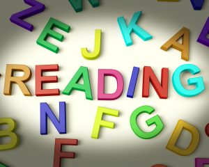 The word READING spell in colorful, kid's letters with other letters lying around it.